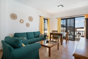 Una sala de estar con sofá, una mesa de centro y una zona de comedor con sillas y una mesa.