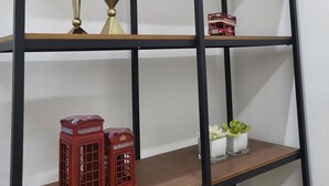 Uma estante de madeira com vários objetos decorativos, incluindo uma cabine telefônica vermelha e um modelo pequeno de ônibus vermelho.