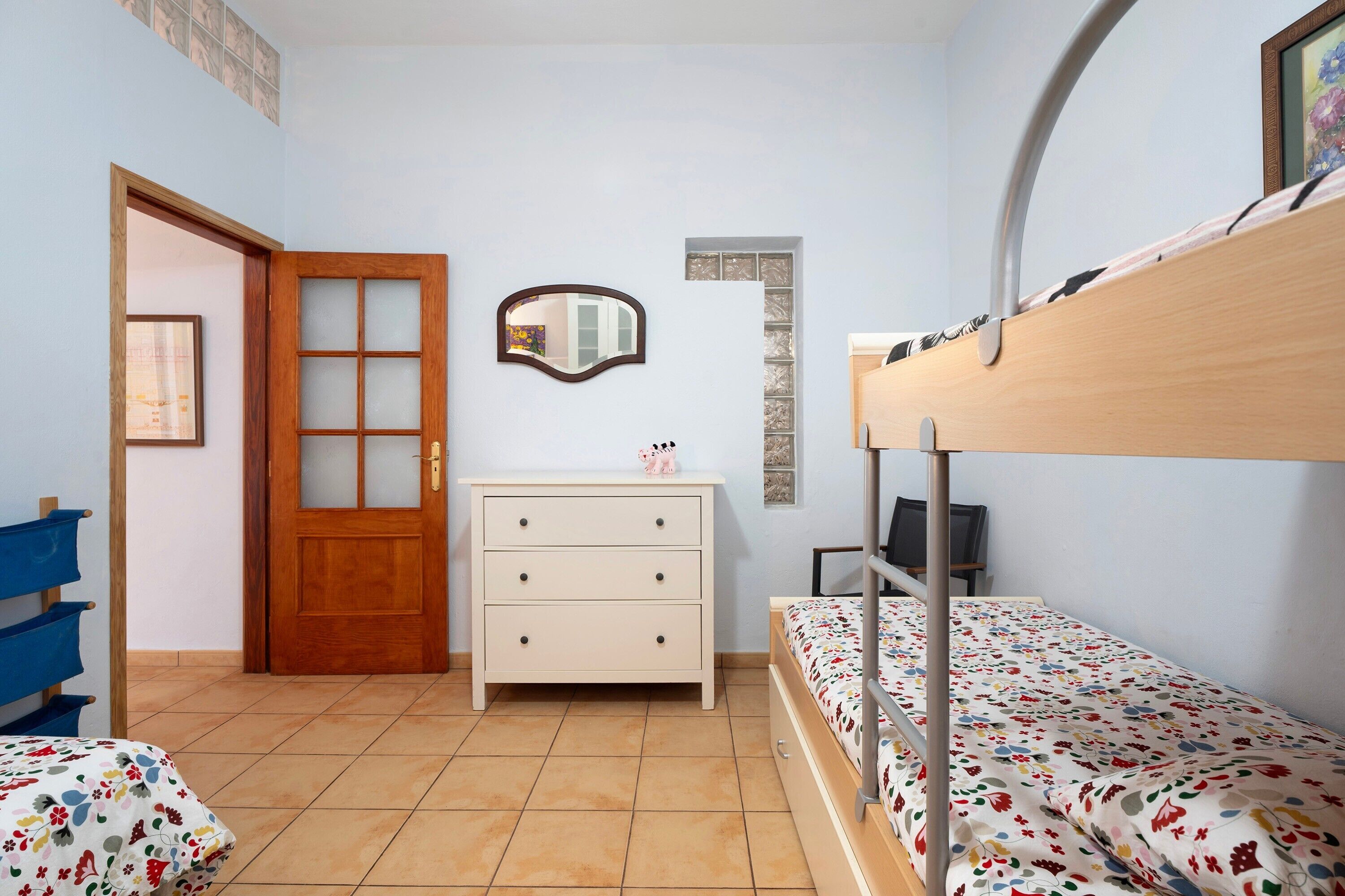 A room with a bunk bed, a wooden dresser, a mirror, and a door.