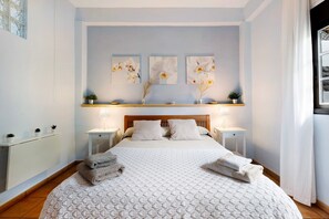Ein Schlafzimmer mit einem Bett, Nachttischen, einem Schminktisch und einer Kommode sowie Wandbildern.