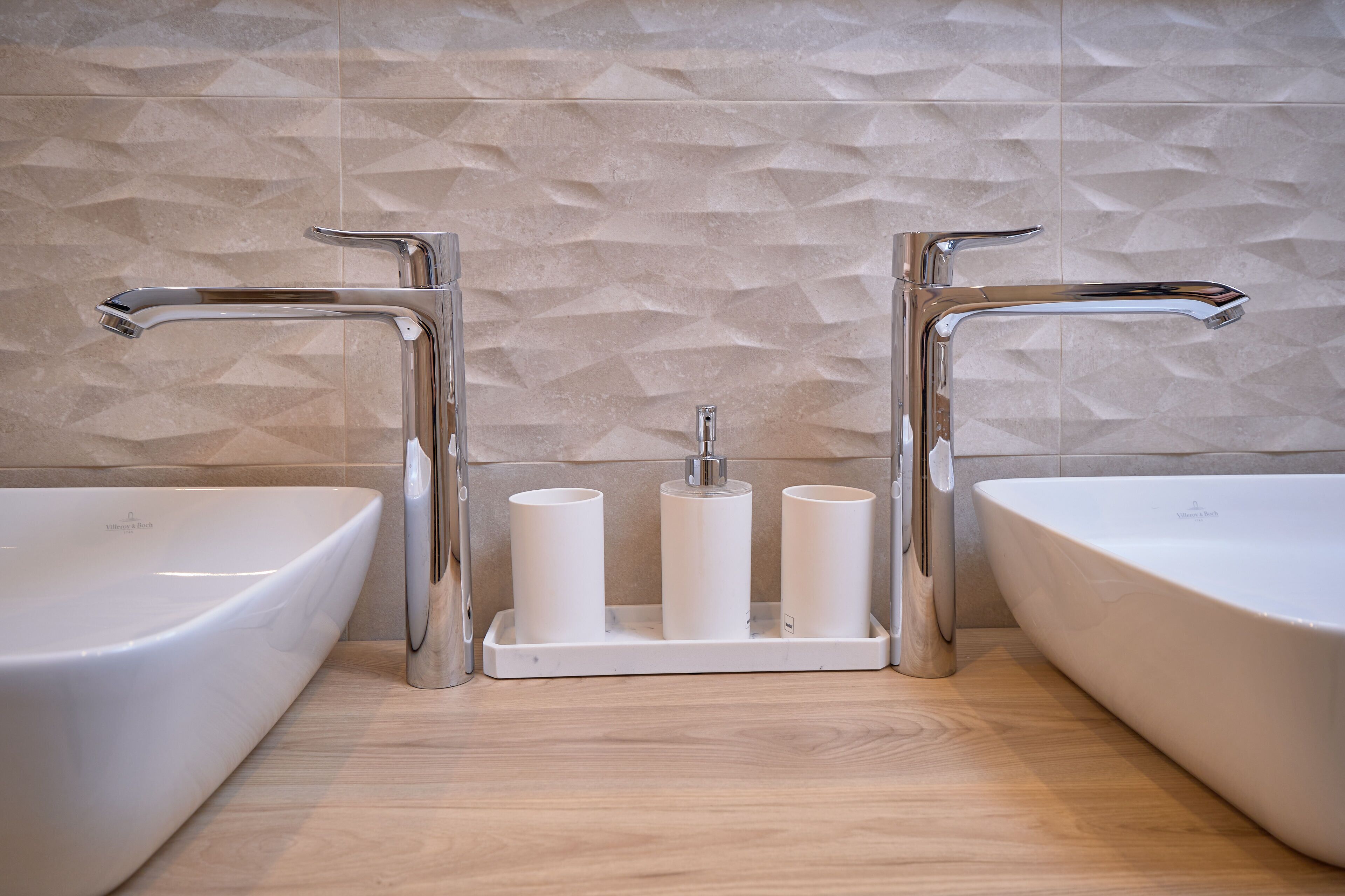 A bathroom with two sinks, a towel rack, and a textured wall.