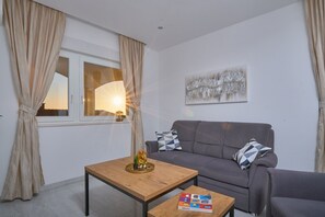 Un soggiorno moderno con un divano grigio, un tavolino in legno e un piccolo tavolo con oggetti decorativi.