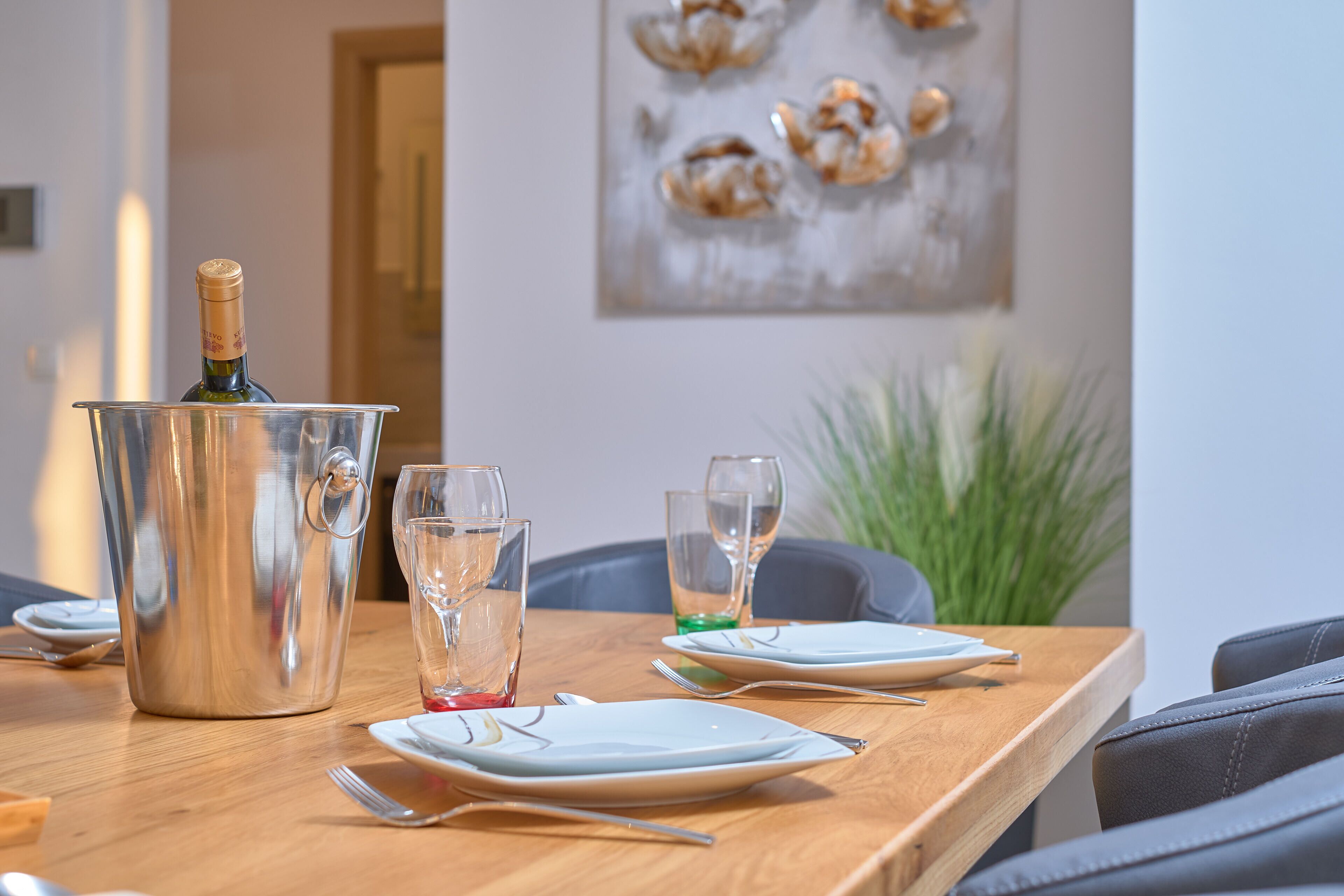 Une table à manger avec une bouteille de champagne, des verres et des couverts.