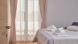 A bedroom with a bed, a door, and a window with curtains.