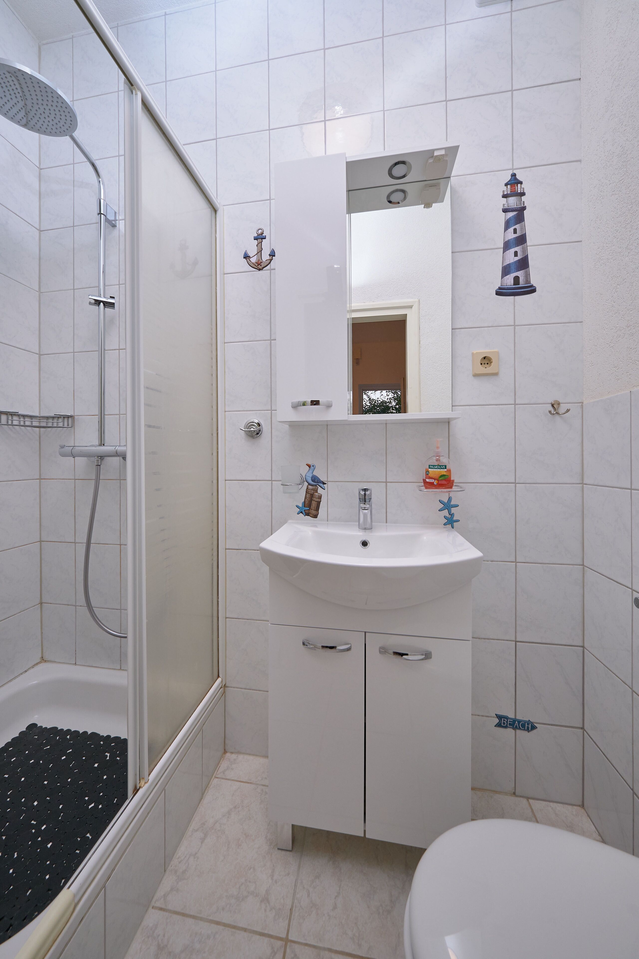 A bathroom with a shower, sink, and toilet.