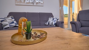 A modern living room with a grey sofa, a wooden coffee table with a glass tray, a cactus, and decorative items.