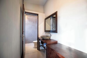 Een moderne badkamer met een stenen wastafel, een houten wastafelmeubel en een grote spiegel.