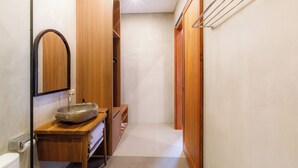 Un baño con tocador de madera, un espejo grande y un perchero para toallas.