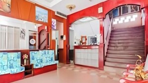 Un vestíbulo amplio con una recepción, una escalera y piso de baldosas.