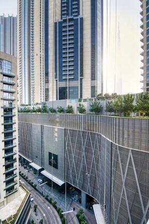 A modern high-rise building with a unique facade featuring a grid-like pattern and a curved structure. - Amazing 1 BR Apartment Damac Mall Street (Dubai)