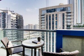 A balcony with wicker furniture, a table, and a book. - Amazing 1 BR Apartment Damac Mall Street (Dubai)