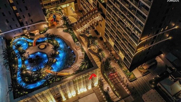 A hotel with a rooftop pool surrounded by palm trees and a well-lit walkway.