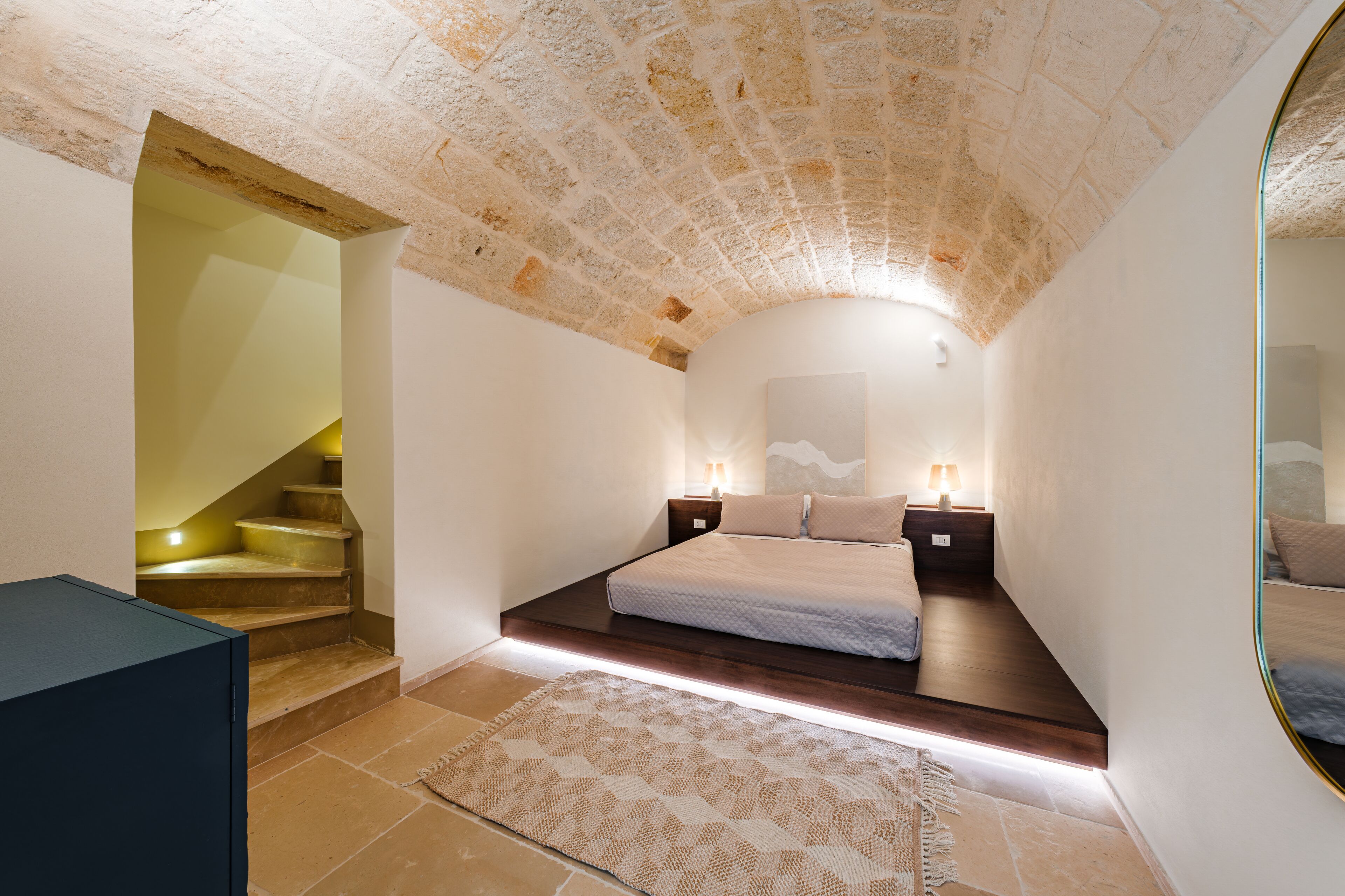Una camera da letto con soffitto in pietra, un letto con testiera, comodini e una scala.