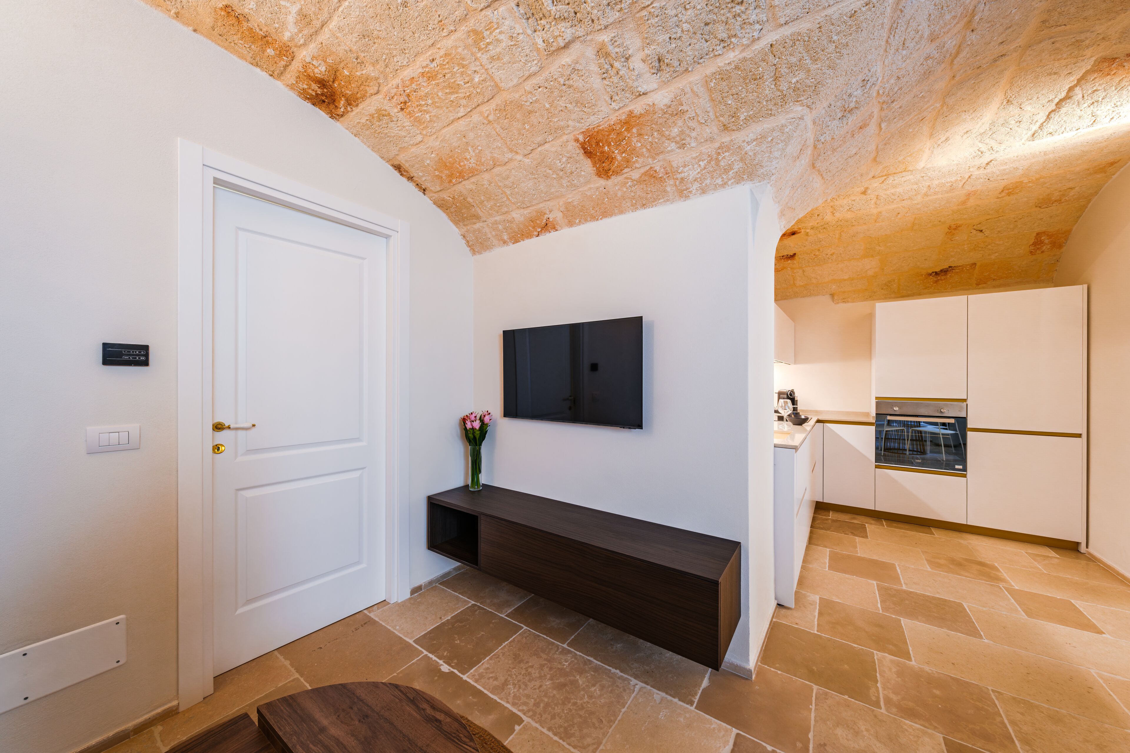 A modern kitchen with a stone ceiling, a built-in oven, and a white door.