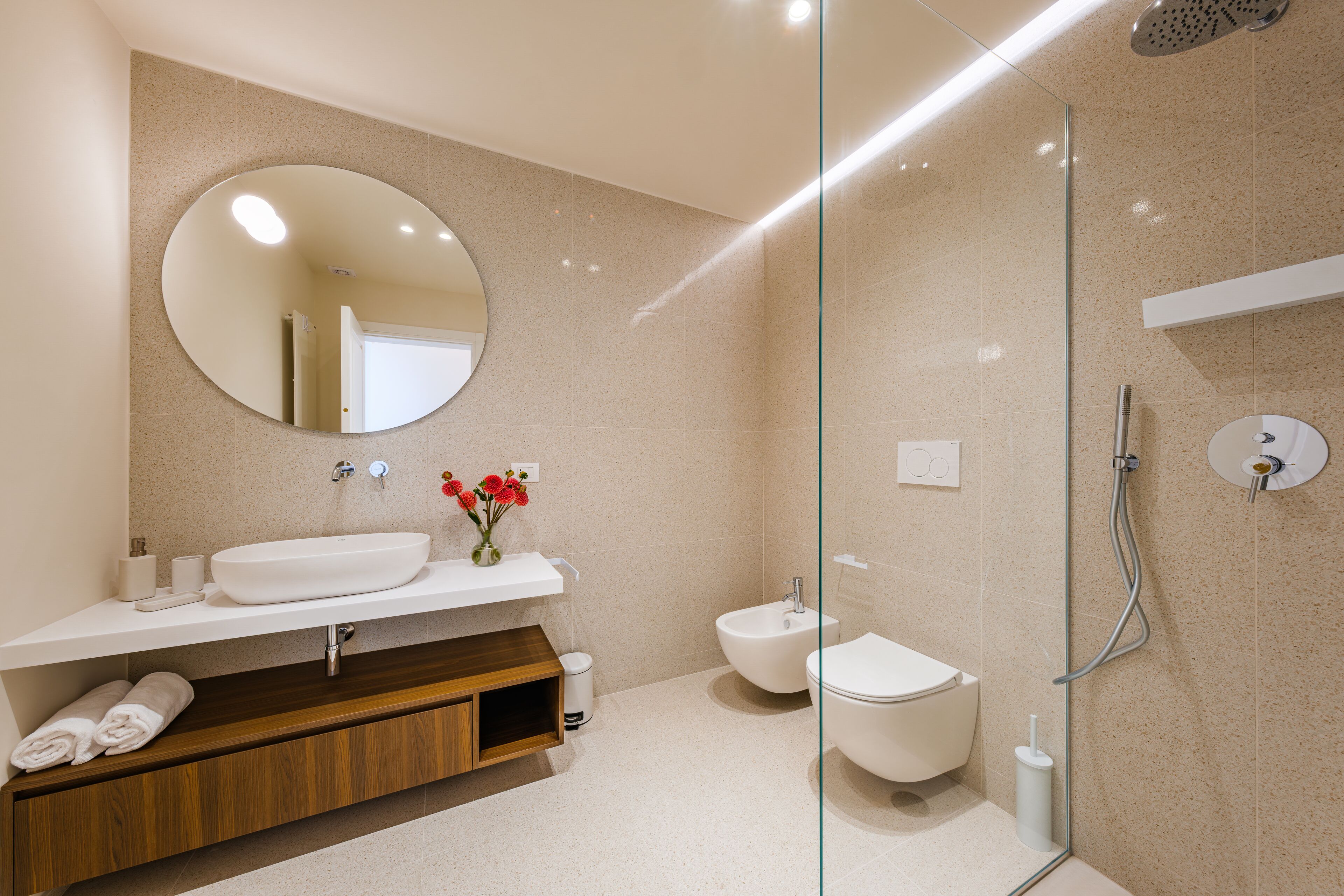 Une salle de bain moderne avec un grand miroir, un lavabo, un bidet et une douche.