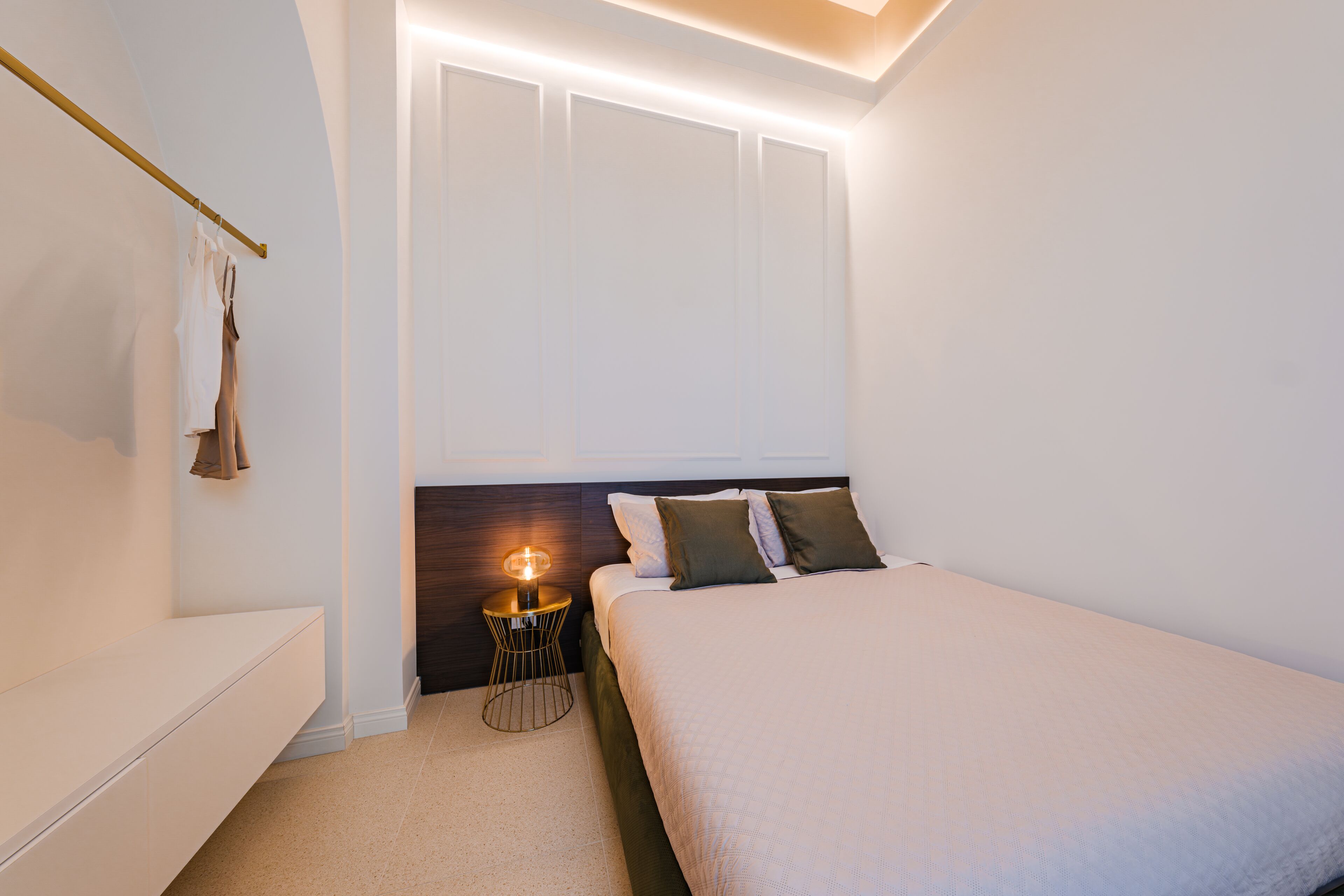 A bedroom with a bed, bedside table, and a hanging light fixture.