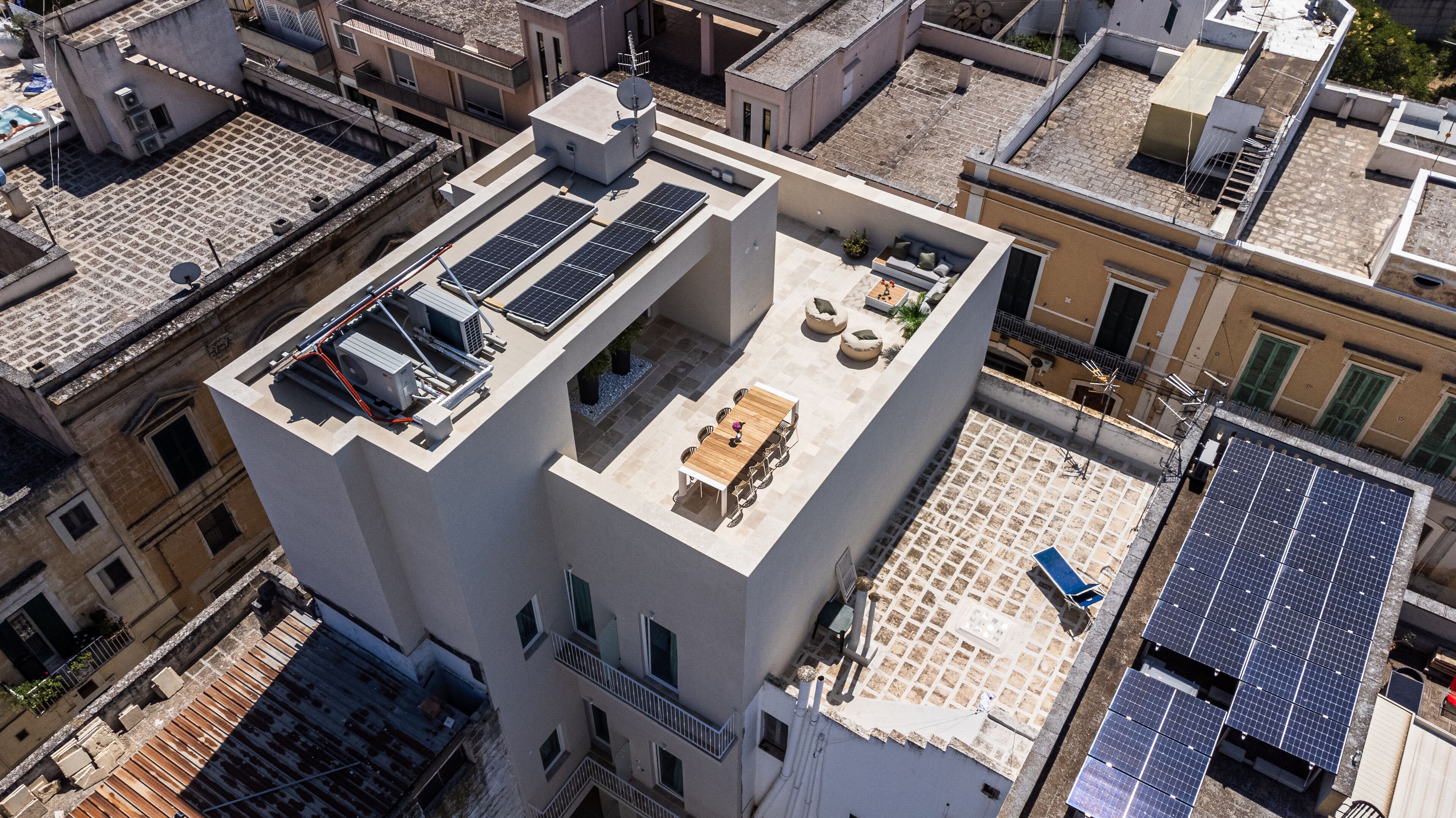 A rooftop terrace with solar panels, a dining table, and chairs.