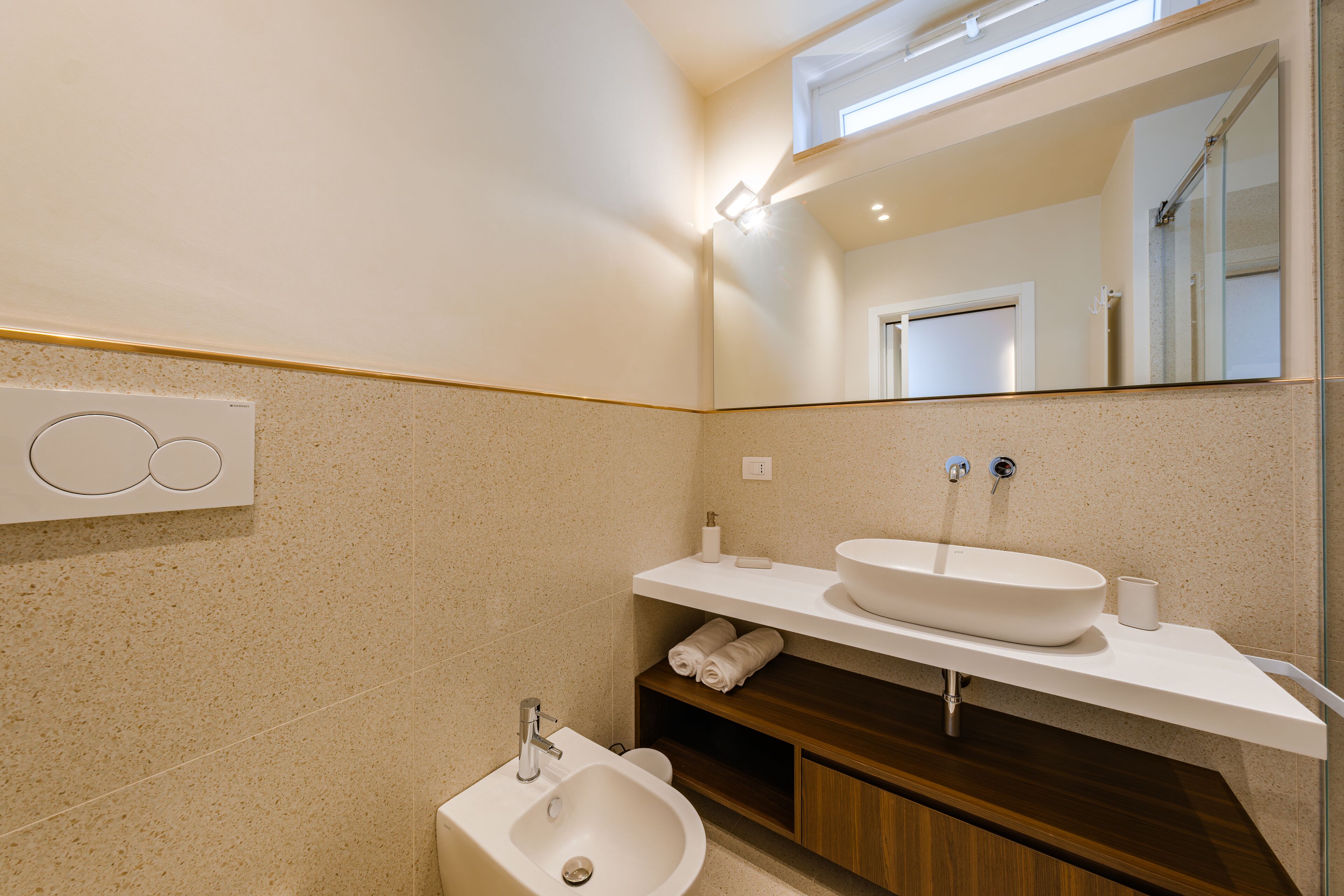 A modern bathroom with a freestanding sink, a mirror, and a toilet.