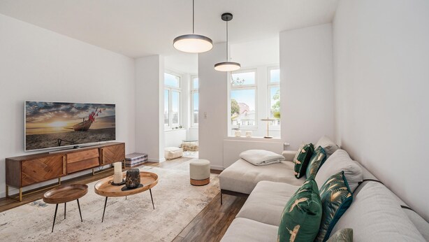 Una sala de estar moderna con sofá, mesa de centro y televisor.