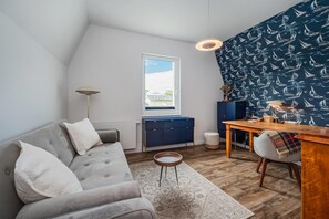 Ein modernes Wohnzimmer mit einem grauen Sofa, einem Holzesstisch und einer Wand mit Musterung.