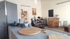 A kitchen with a refrigerator, a cutting board, a coffee maker, and a kettle.