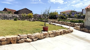 A well-maintained garden with a stone wall, a paved pathway, and a potted plant.