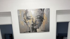 Un interior moderno con una mesa y sillas grises, un cuadro abstracto grande en la pared, y una pared de acento azul al fondo.