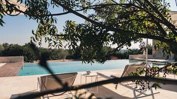 Een seizoensgebonden buitenzwembad, ligstoelen bij het zwembad