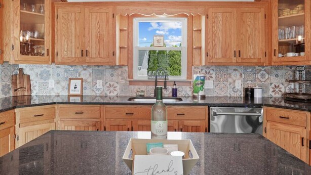 Una cocina con armarios de madera, encimera de granito y ventana con vistas a zonas verdes.
