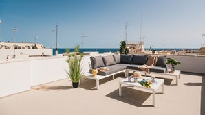 A rooftop terrace with a sofa, coffee table, and potted plants. - Le Terrazze di Don Nino (Polignano a Mare)