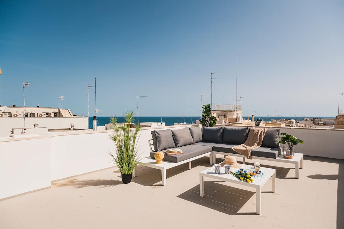 Une terrasse sur le toit, aménagée avec un canapé, une table basse et des plantes en pot.