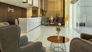 A modern lobby with grey armchairs, a reception desk, and a glass wall. - SJ Miracle Hotel (Hat Yai)