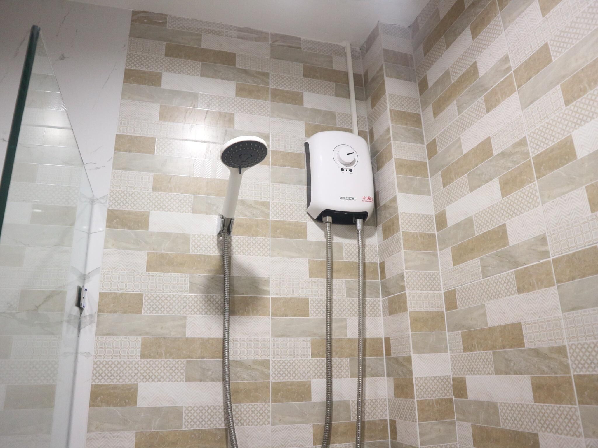 Zona de ducha con cabezal de ducha de mano y panel de control en la pared.