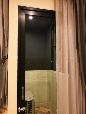 A room with a glass door, a small heater, and a curtain. - SJ Miracle Hotel (Hat Yai)