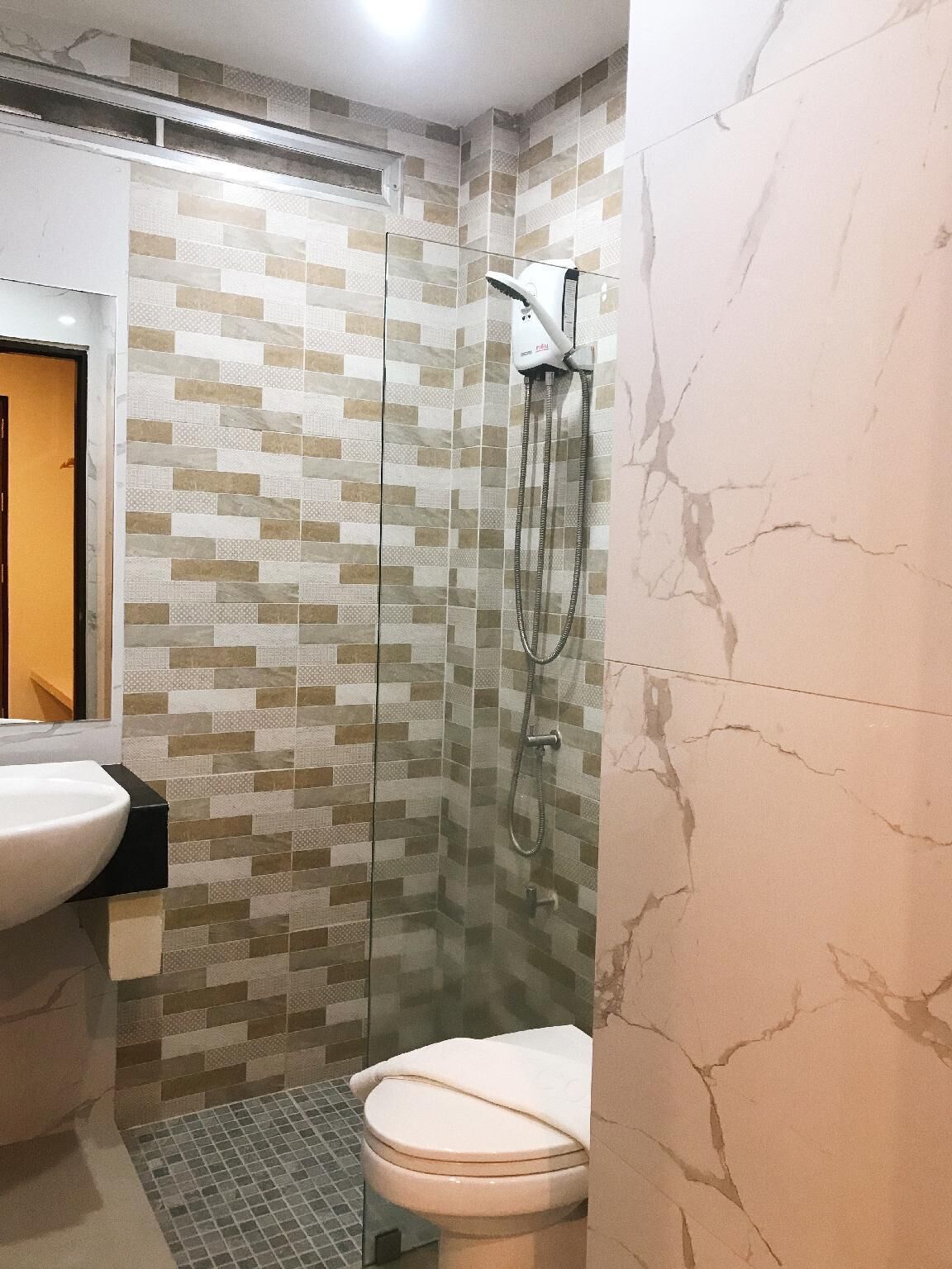 A bathroom with a glass-enclosed shower, a white sink, and a toilet.