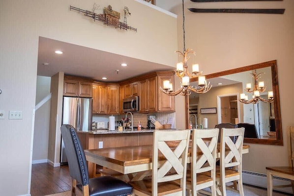 A spacious kitchen with wooden cabinets, a central island, and a chandelier.