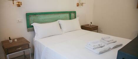 A neatly made bed with white linens, two bedside tables, and a green-painted headboard.