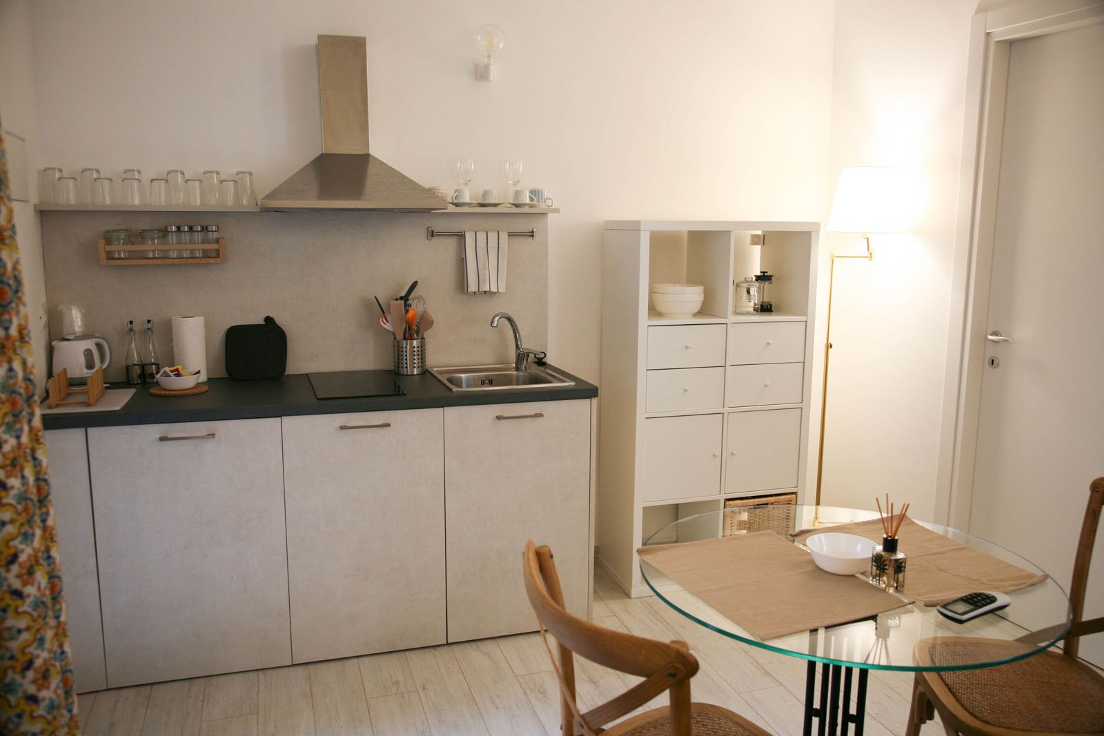 A modern kitchen with a central island, a built-in stove, and a dining area with a glass table and chairs.