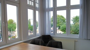 Une pièce avec une grande fenêtre, une table en bois et une chaise noire.