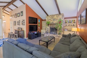 A cozy living room with a stone fireplace, a large flat-screen TV, and a comfortable sofa.