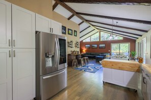 A modern kitchen with stainless steel appliances, a bar area, and a view of the outdoors.