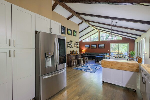 A modern kitchen with stainless steel appliances, a bar area, and a view of the outdoors.