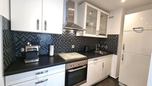 Een moderne keuken met witte kastjes, een zwart aanrecht, een koffieapparaat en een inbouwoven.