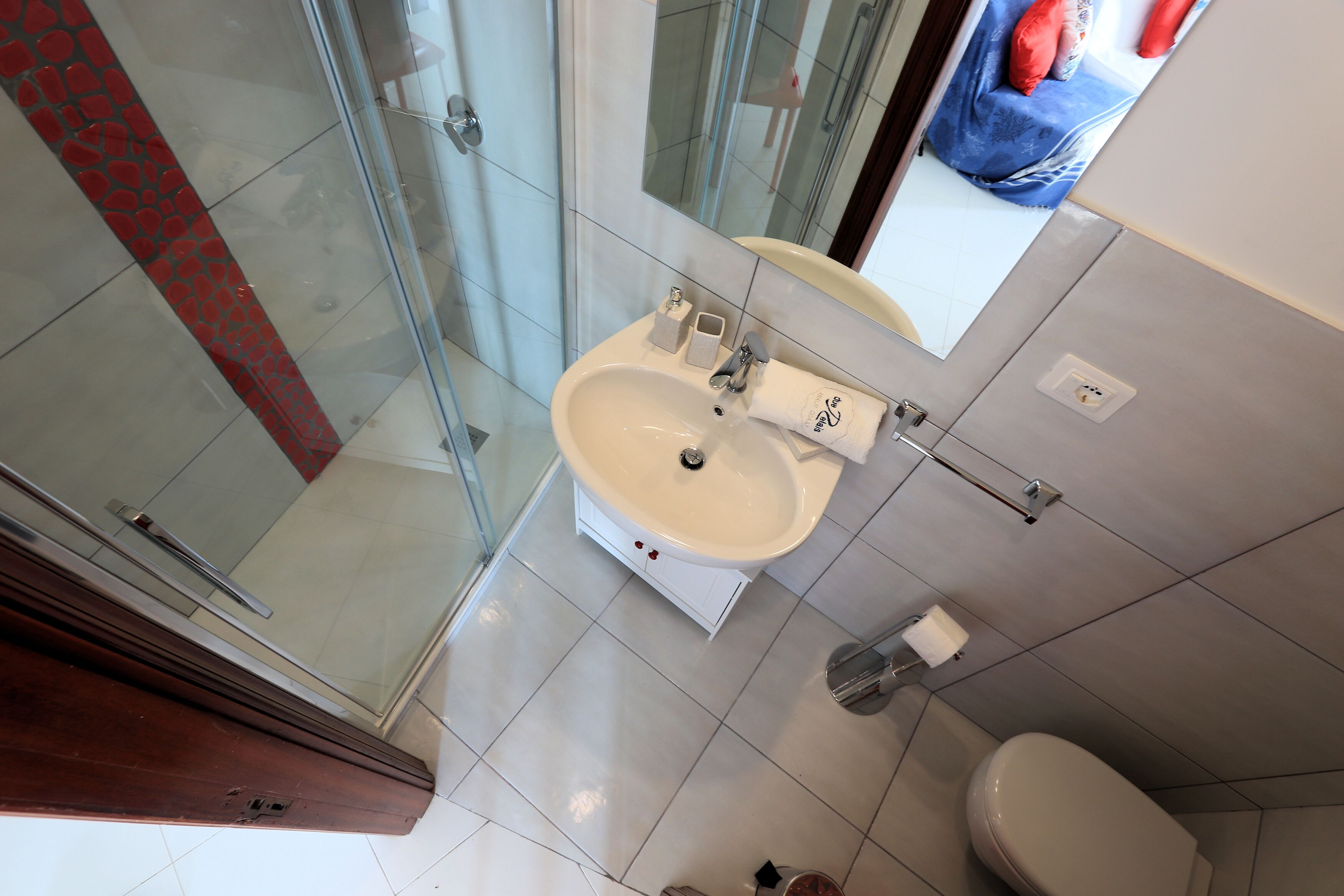 Ein Badezimmer mit Duschkabine aus Glas, Waschbecken mit Spiegel und Toilette.