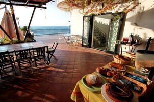 Una terraza con una mesa preparada para el desayuno, con vistas al mar.