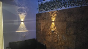 A seating area with a stone wall and two wall-mounted lights. - Cheirinho a Mar House (Nazaré)