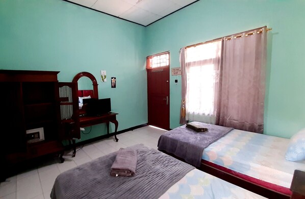 Un dormitorio con dos camas, un escritorio, un armario y una ventana con cortinas.