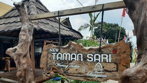 A wooden sign with the text "NEW TAMAN SARI Warung Tuber & Cingalows" indicating a location or establishment. - New Taman Sari Homestay (Pemenang)