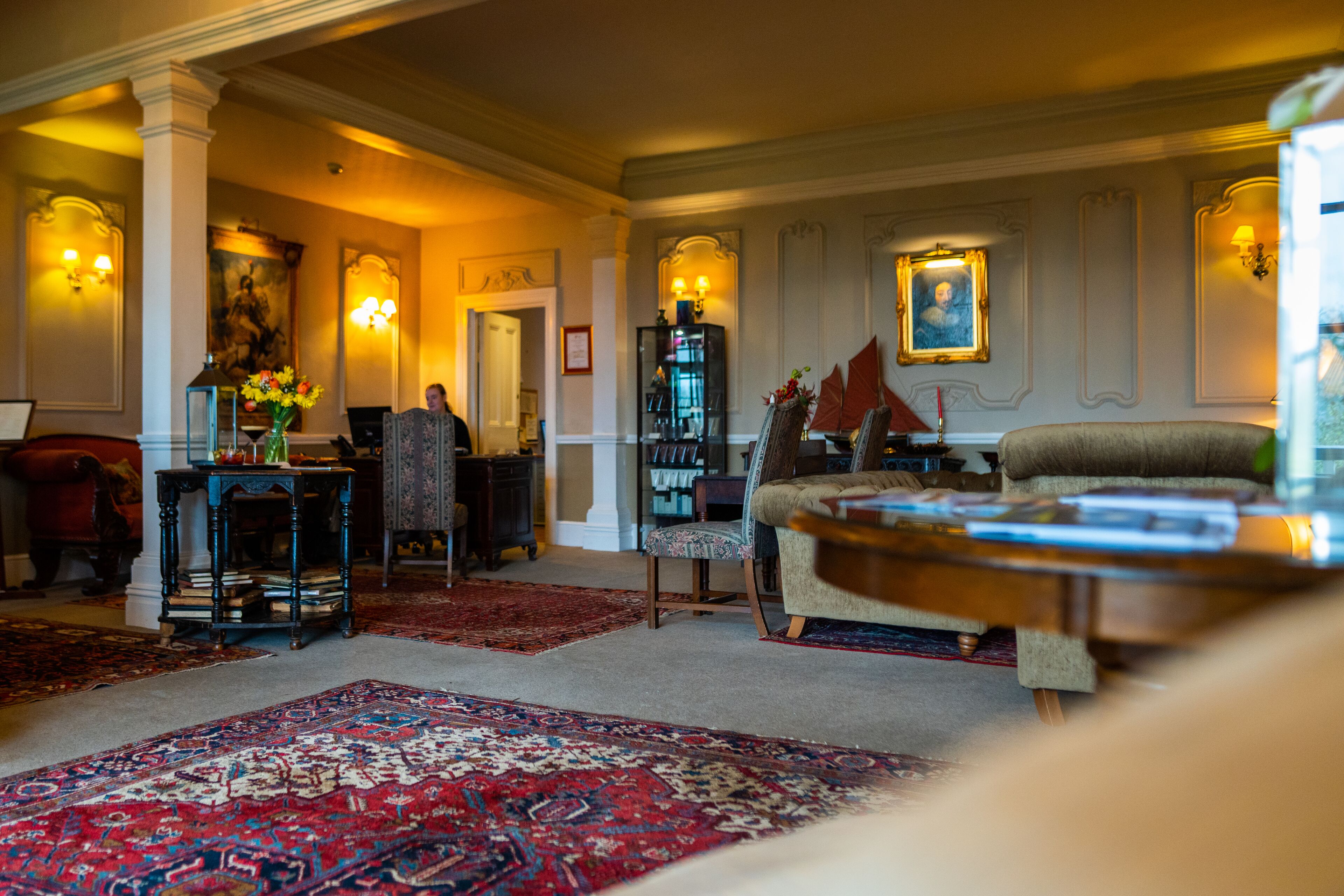 A spacious living room with a large red carpet, a wooden coffee table, and a comfortable armchair.
