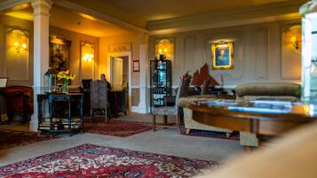 A spacious living room with a large red carpet, a wooden coffee table, and a comfortable armchair.